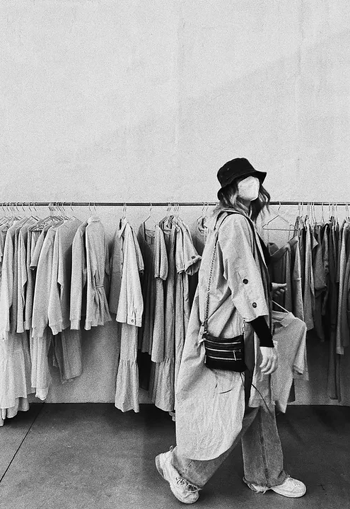 Ein Schwarz-Weiß-Foto einer Frau, die vor Kleiderständern läuft.